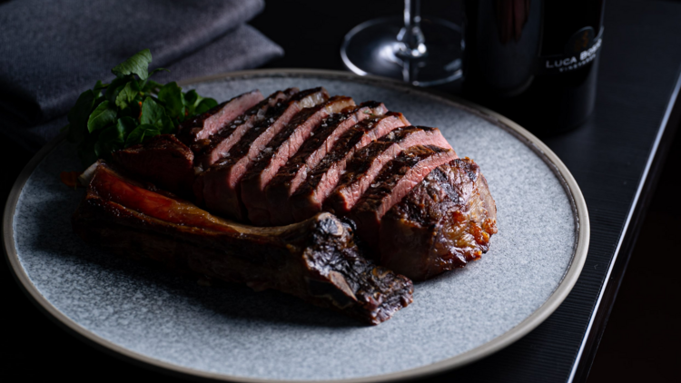 A wagyu steak t rib eye is sliced on a slate plate, the bone to the side