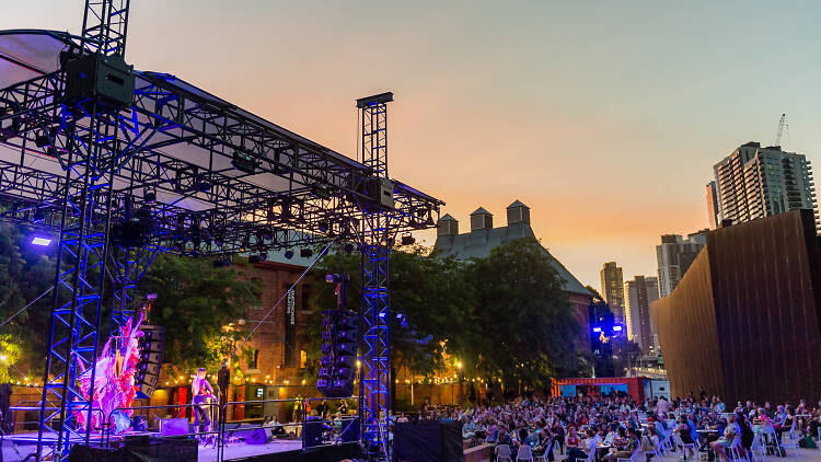 Nai Palm performing at dusk on an outdoor stage in Malthouse Theatre's courtyard