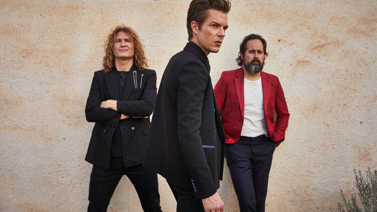 The Killers band posing against a wall