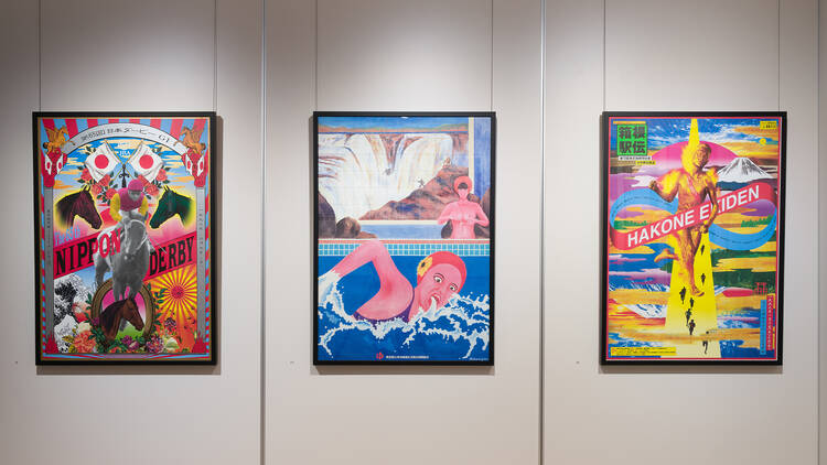 Three colourful framed posters hanging on a white gallery wall.