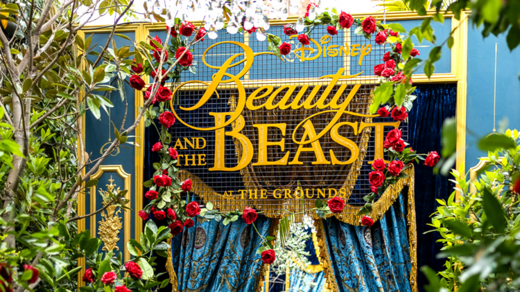 A gold sign reads Disney's Beauty and the Beast at the Grounds