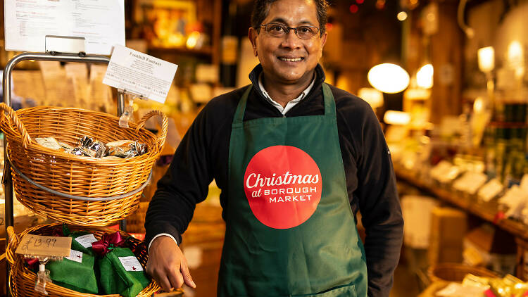 Ratan Mondal, owner of Tea2you standing by his stall at Borough Market wearing a Christmas apron