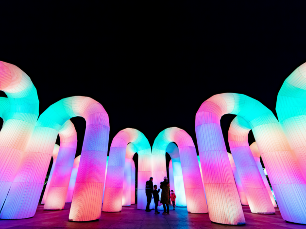 Sky Castle Multi coloured inflatable arches light up against a black sky, a family stand in front
