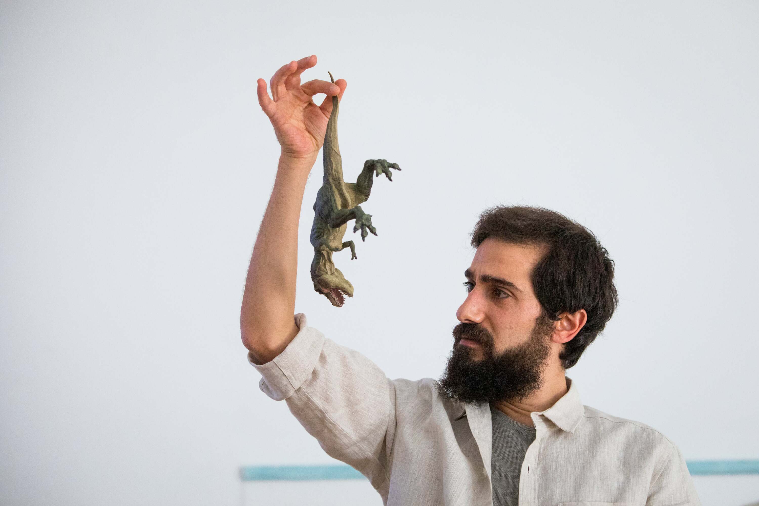 homem a agarrar um dinossauro de plástico