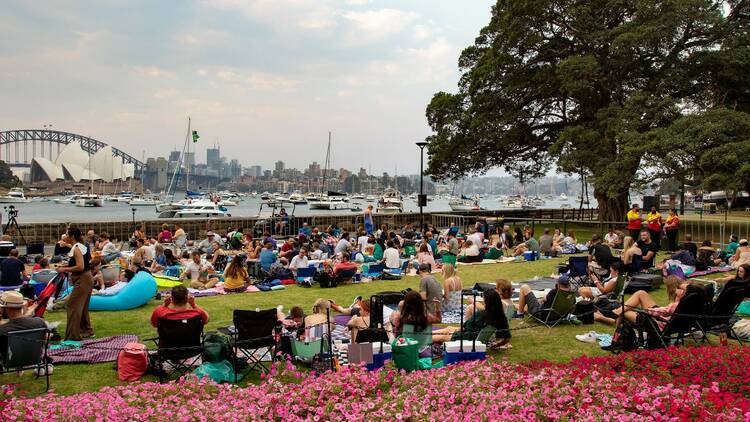 People relax on the grass facing the harbour waiting for the fireworks.
