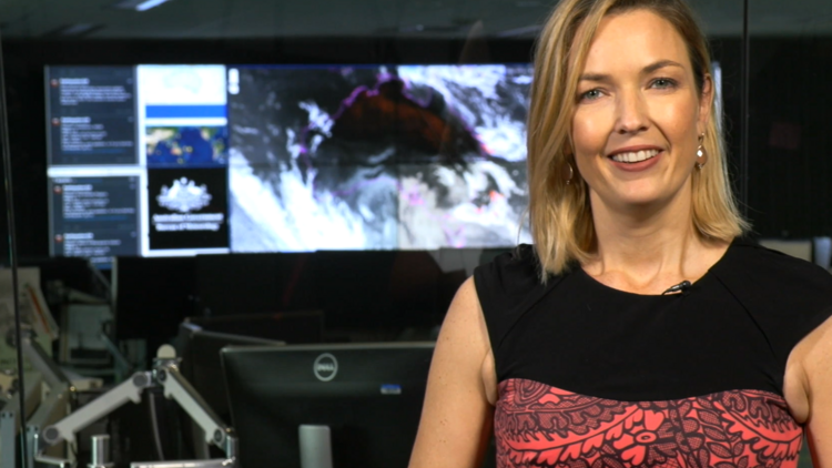 Meteorologist Sarah Scully standing in front of a computer with weather patterns.