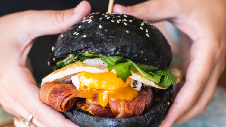A black charcoal bun with crisp bacon, an oozy egg and rocket 