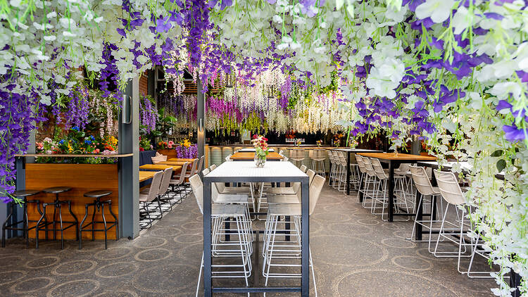 Purple, white and yellow wisteria hangs from the ceiling over tables and chairs in the Smith atrium.