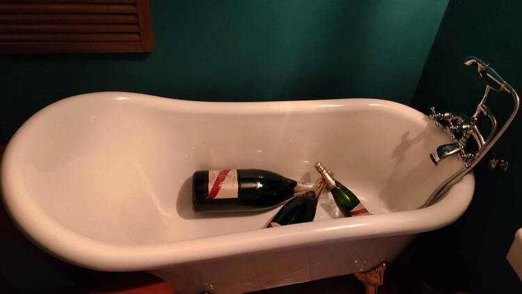 A ceramic bathtub with three large champagne bottles inside