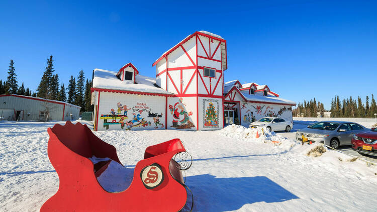 A photo of a red sleigh in front of North Pole, Alaska's The Santa Claus House