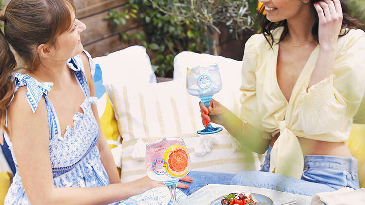 Two women sitting at a table enjoying drinks and food.