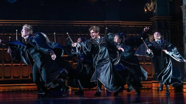 A scene from Harry Potter and the Cursed child in which Hogwarts students run with their wands outstretched