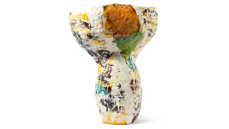 A tall ceramic vessel with a cup shape at the top with a colourful orange, yellow, blue and brown abstract glaze.