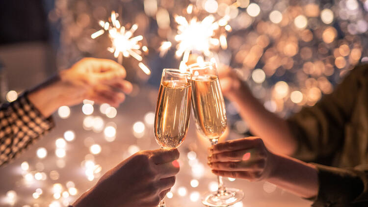 Two people cheersing champagne on new year's eve with sparklers