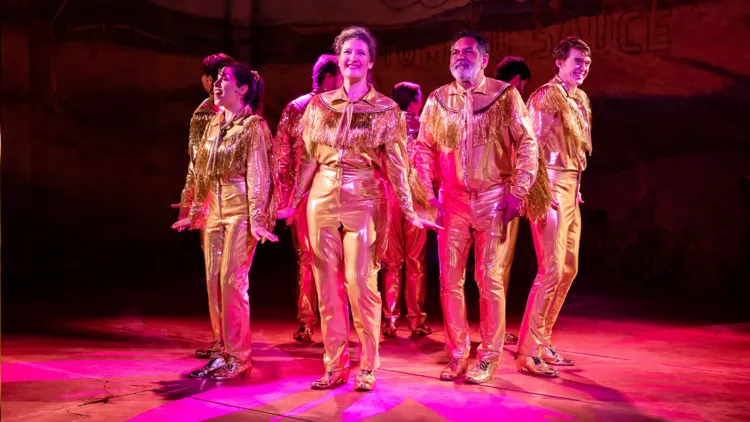 Virginia Gay and the cast of The Boomkak Panto in gold western outfits.