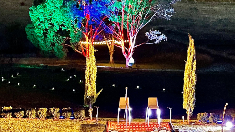At night a stage in a paddock with trees illuminated in the background