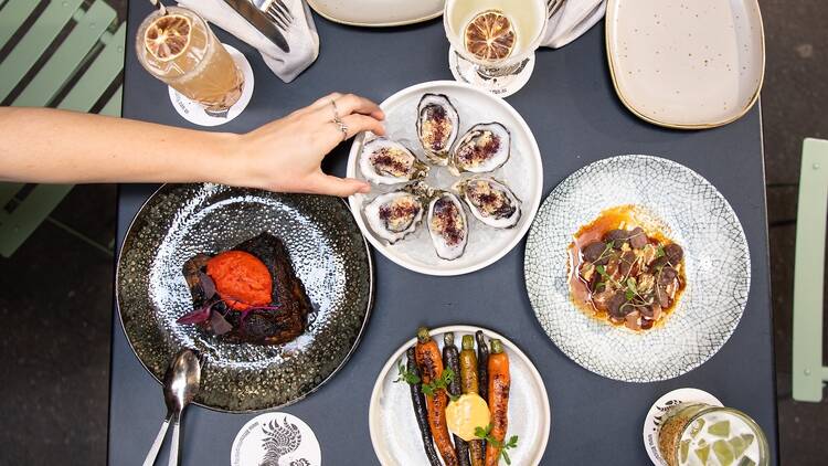 An overhead shot of a lunch table with oysters, roast carrots and more 