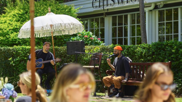 Picnickers sit under white umbrellas on the lawn at Chiswick