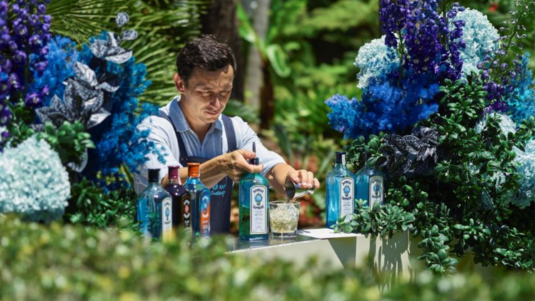 A bartender makes drinks between floral arrangments