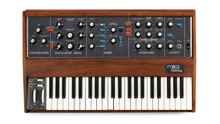 A wooden synthesiser with a black board containing many knobs.