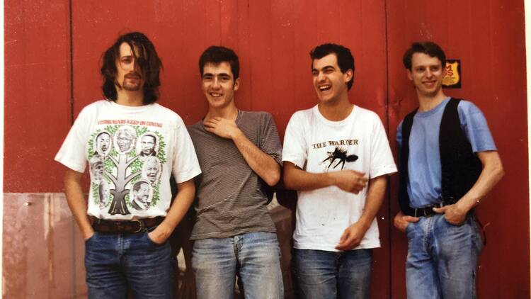 The Warner Brothers band standing against a red painted backdrop.