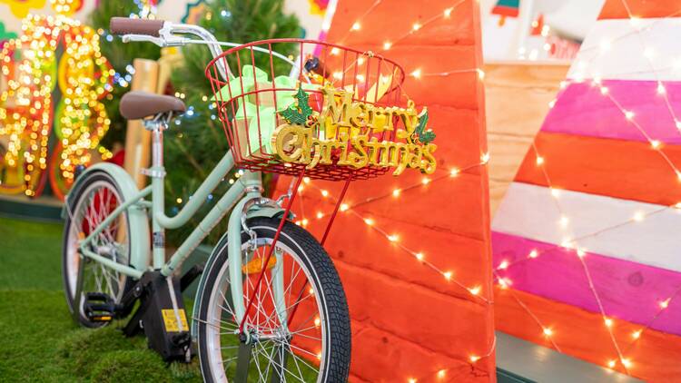 A photograph of a Santa set with christmas lights and a bicycle