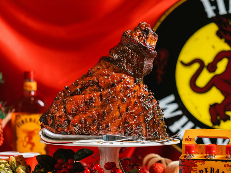 A glazed ham on a tower with a bottle of Fireball in the background