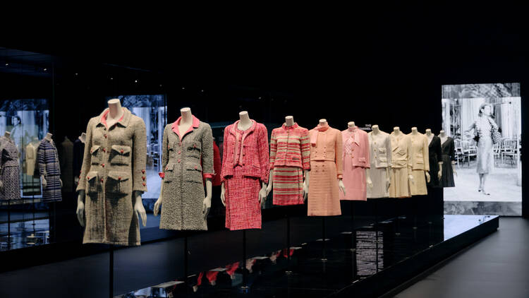 A row of mannequins wearing various Chanel tweed suits