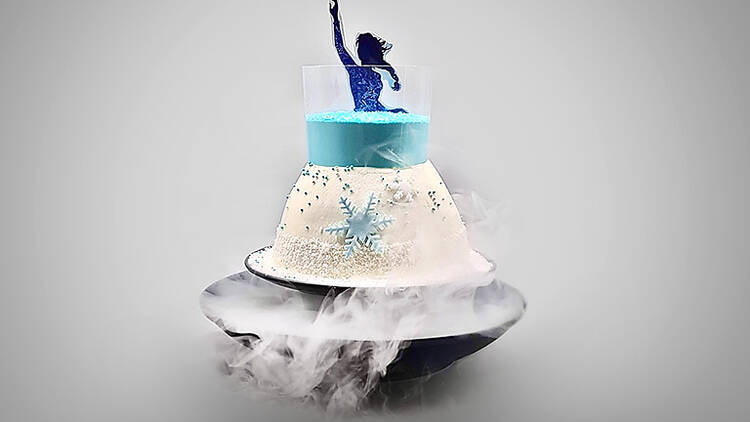A blue and white ice-cream cake with smoke billowing from the bottom