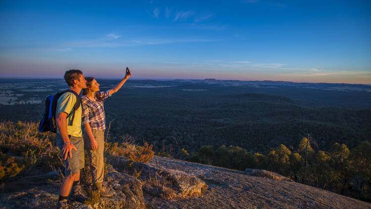 A man and a woman take a selfie at the top of a mountain lookout