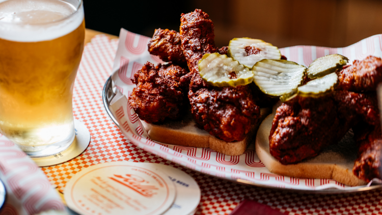 Fried chicken on white bread with pickles and a beer