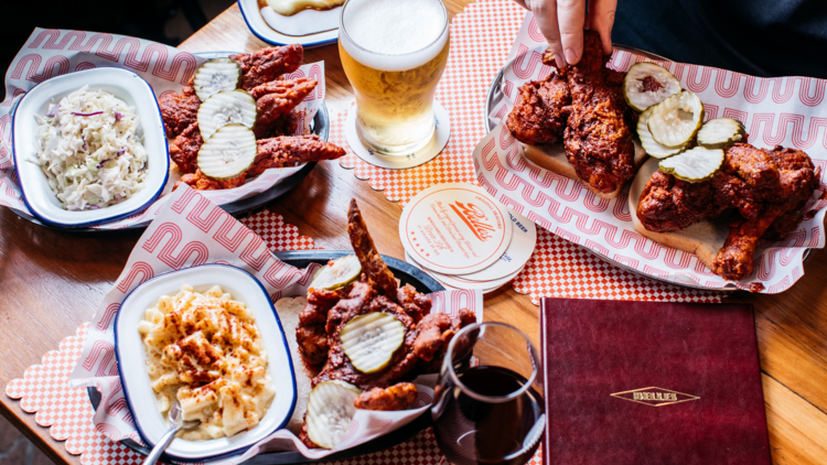 A flat lay with fried chicken, beer, mac and cheese and coleslaw