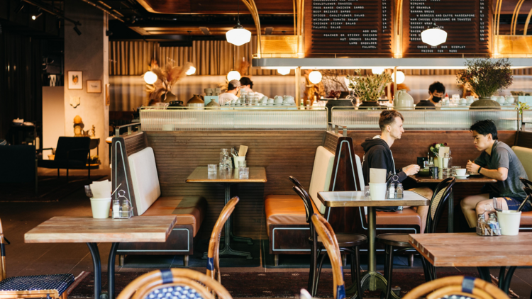 Two men sit across from each other in a booth