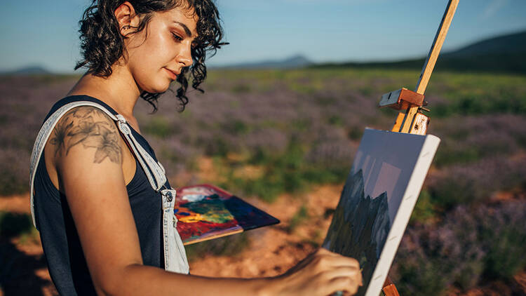 Person painting on an easel in a field of lavender