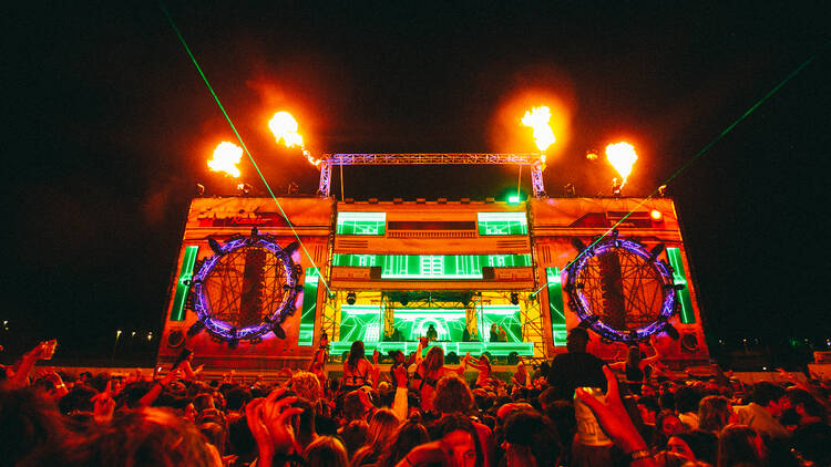 A giant lit-up stage in the shape of a stereo with a huge crowd moshing out the front