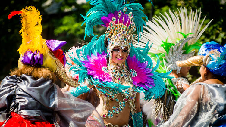 A woman wearing an elaborate turquoise feathered headdress and outfit at Notting Hill Carnival 2017 