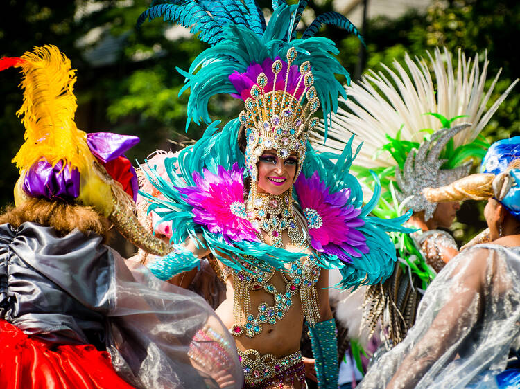 A woman wearing an elaborate turquoise feathered headdress and outfit at Notting Hill Carnival 2017 