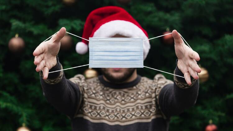 Man holding mask in front of a Christmas Tree