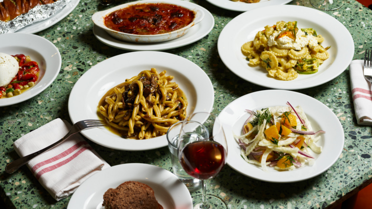 A flat lay of Italian dishes and wine on a green marble table