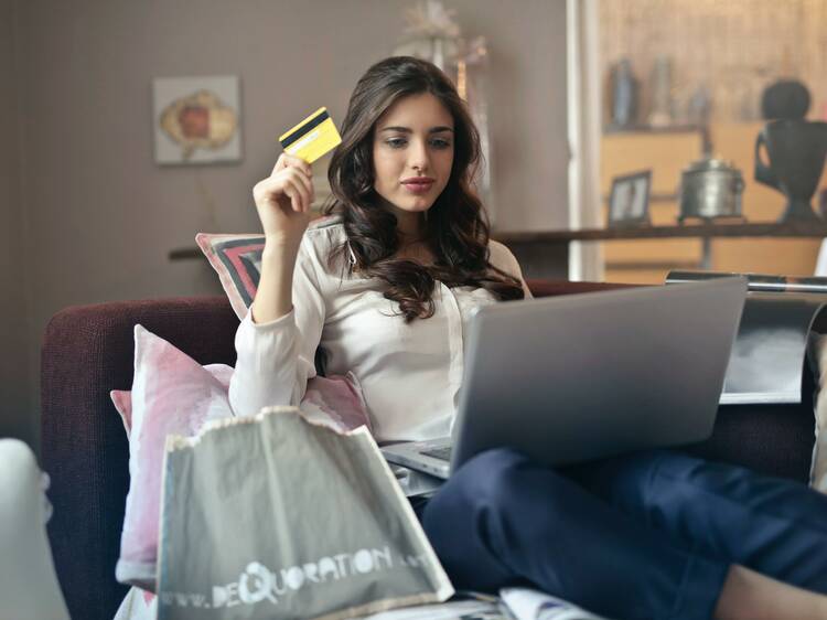 A woman online shopping with her laptop while holding a credit card.