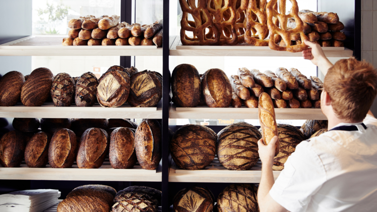 A baker placing baguettes on a shelf