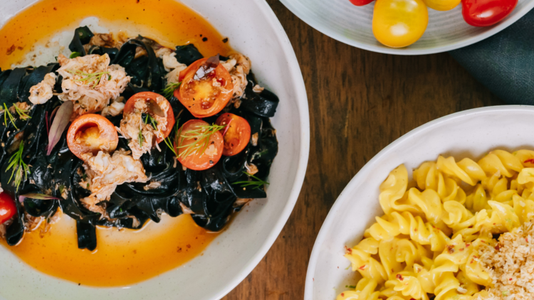Squid ink pasta, spiral pasta and a bowl of tomatoes