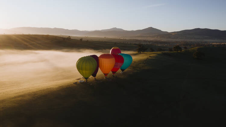 Six colourful hot air balloons prepare to take flight on a misty morning in Victoria's High Country