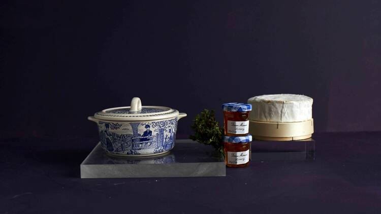A porcelain bowl, two jars of honey and a wheel of soft cheese.