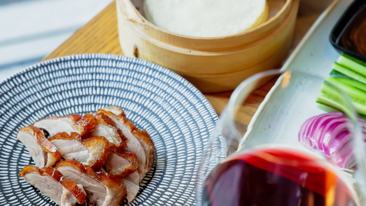 A table with Peking duck and glass of red wine