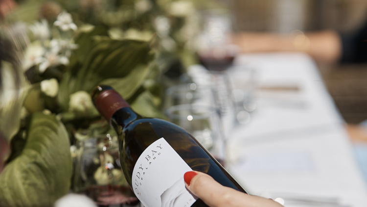 A waiter pouring a glass of wine in front of a table setting of flowers