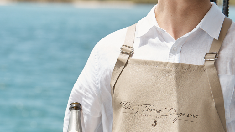 A waiter holding a bottle of sparkling wine in front of the waters