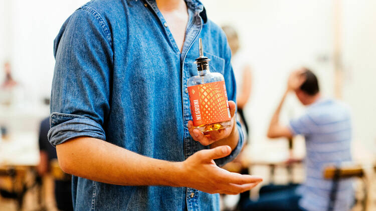 Craft & Co Summer Gin Market. A man visible from the neck to the waist holding a bottle of gin.