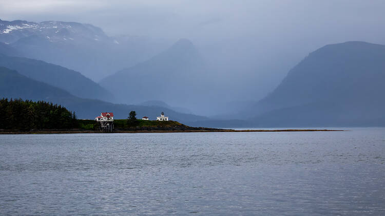 Early on a foggy morning snow on mountains in the background, at Point Retreat Lighthouse, Juneau Alaska. 