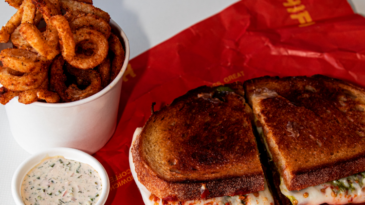 A sandwich with sides of curly fries and ranch sauce from Hi Fi.